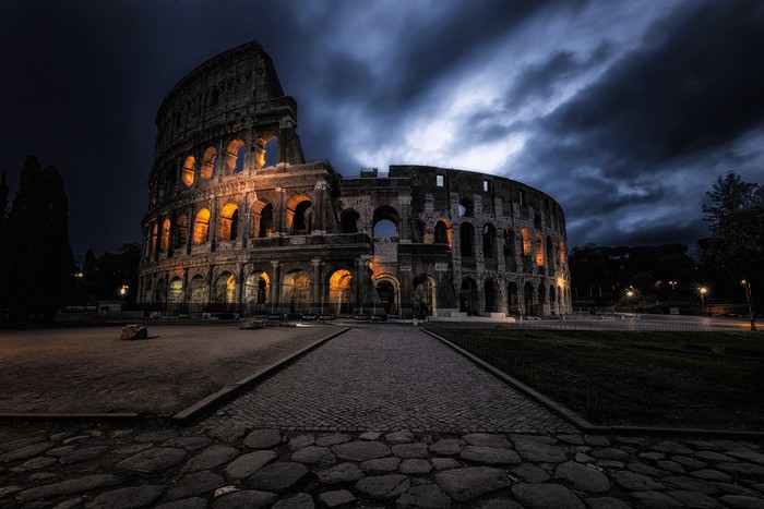 The Colosseum at night under a cloudy sky