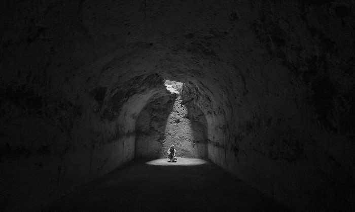 Person in a beam of light in a dark cave