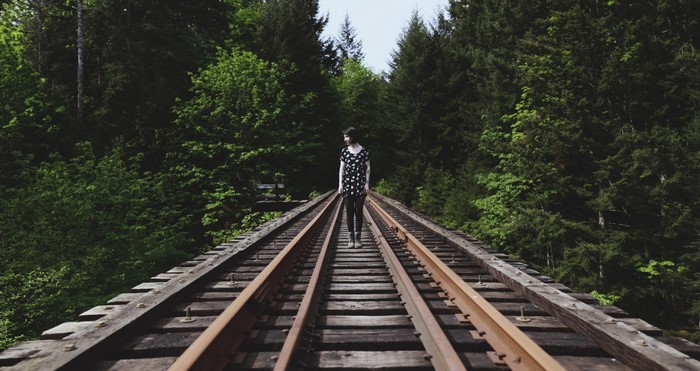 Woman standing on railroad tracks in a forest