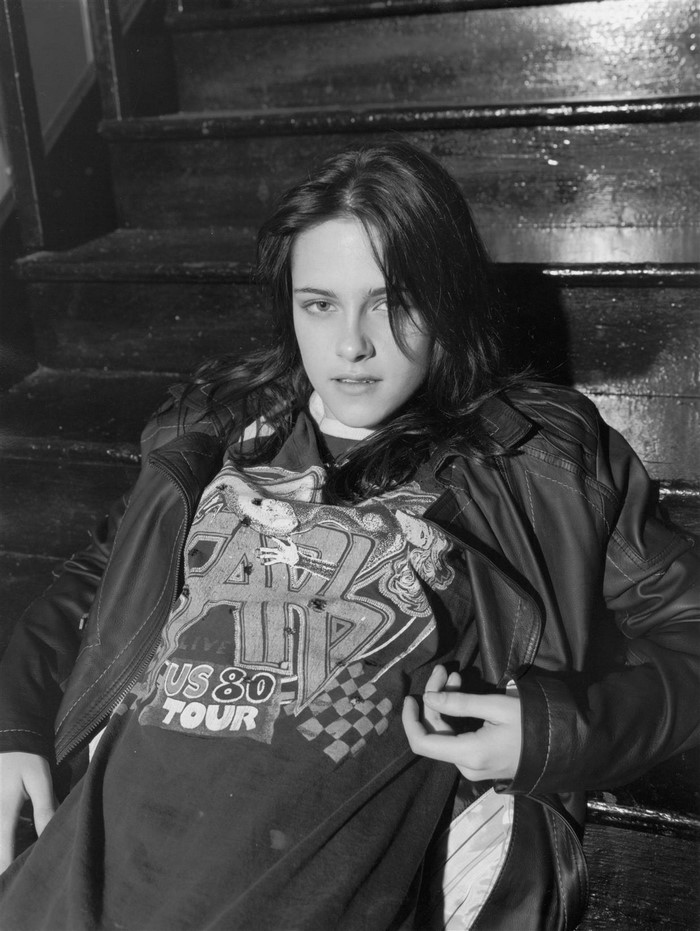 Kristen Stewart sitting on stairs wearing a t-shirt and jacket