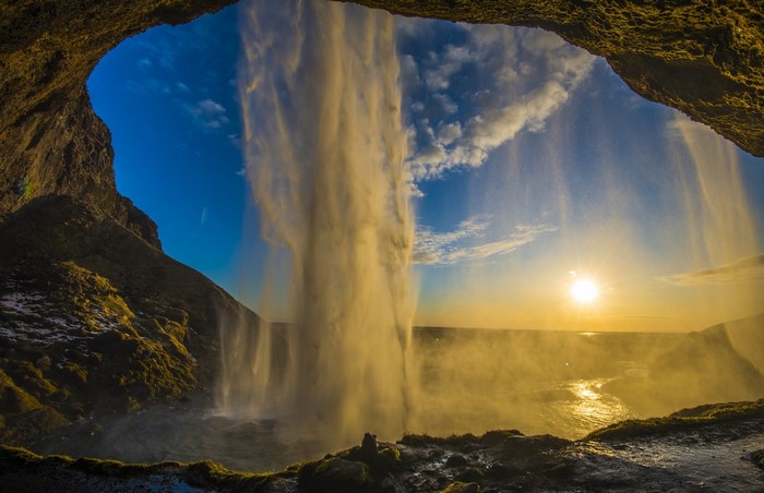 Waterfall seen from a cave in Iceland at sunset