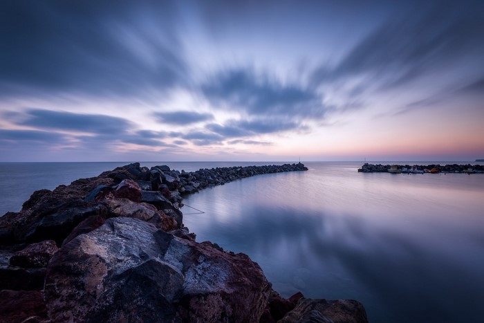 Long exposure of a rocky breakwater at dusk
