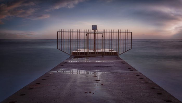 Pier with gate at sunset over the ocean