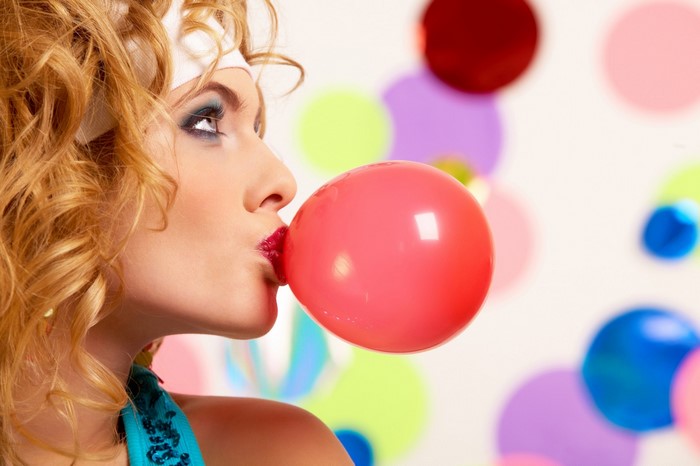 Woman blowing a pink bubble gum balloon