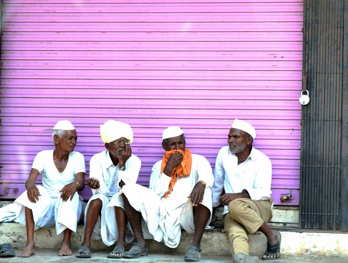 Four elderly men sitting in front of a pink shutter