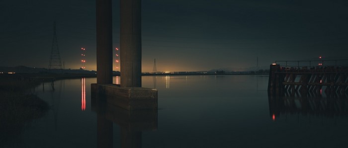 Night landscape with bridge pillars and water reflection