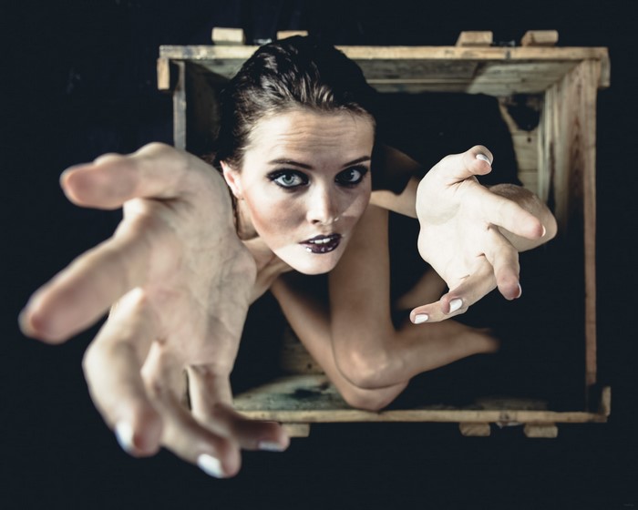 Woman reaching out from a wooden box