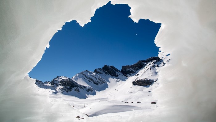 Snowy mountains seen through a hole in ice