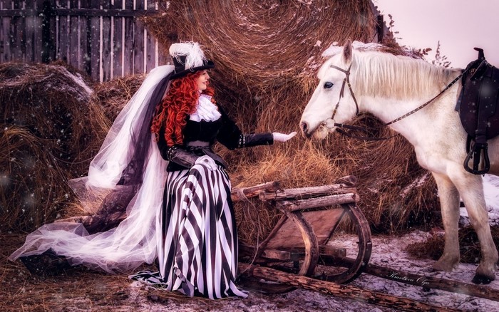 Woman in costume with horse and hay bales in winter