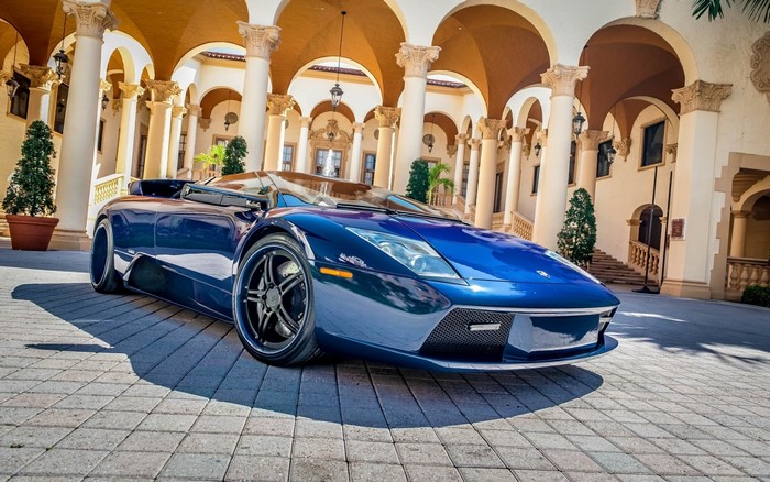 Blue Lamborghini Aventador parked in front of a building with arches
