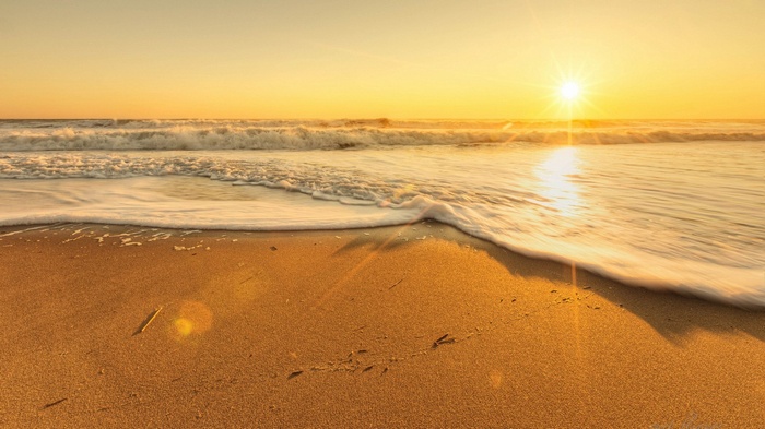 Sunset over a sandy beach with ocean waves
