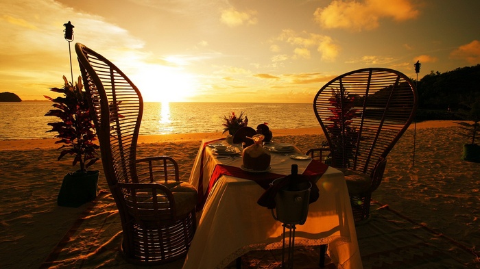 Romantic beach dinner at sunset with two chairs