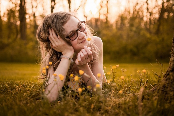 Woman with glasses lying in a field of flowers