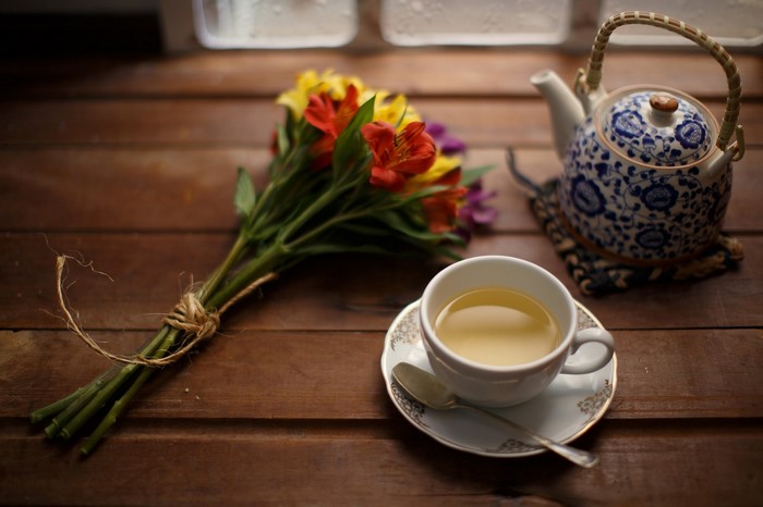 Tea cup and teapot with flowers on a wooden table
