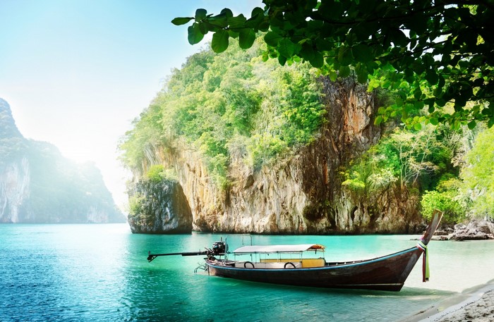 Long tail boat in a tropical bay with limestone cliffs