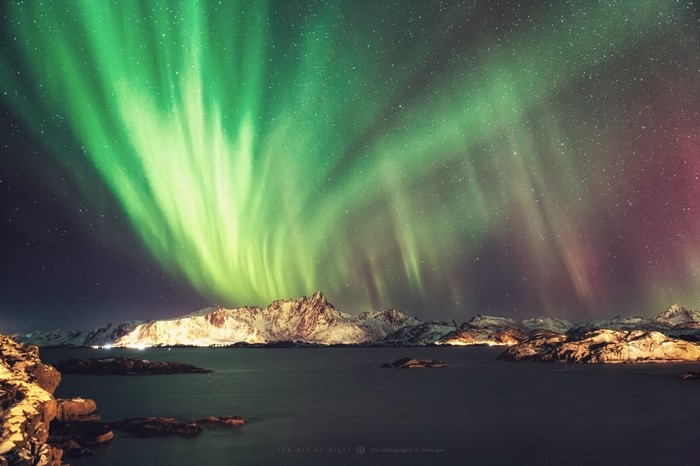 Aurora Borealis over snowy mountains and water