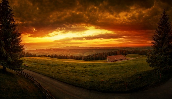 Sunset over rolling hills with a farmhouse