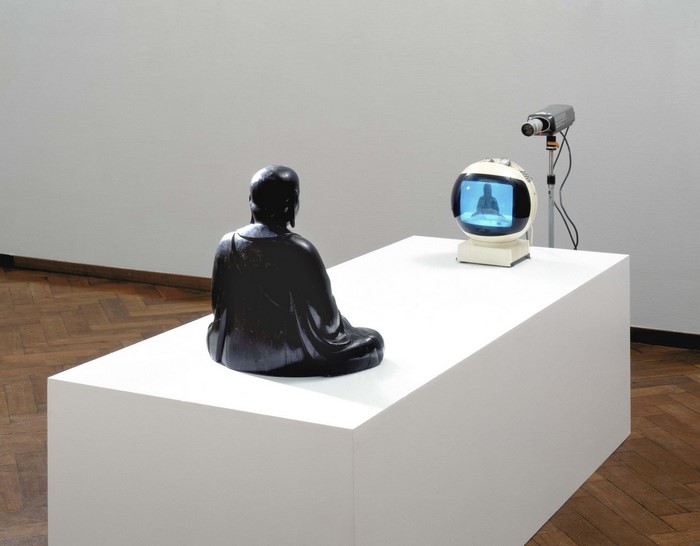 Buddha sculpture on a table with a camera and TV