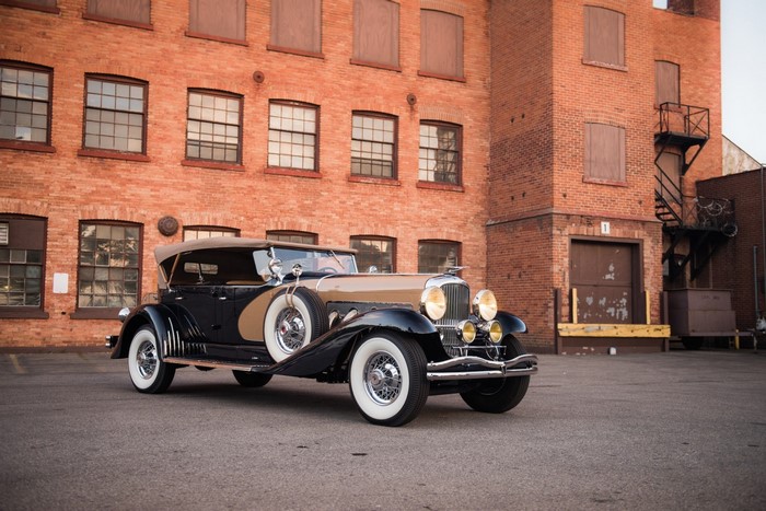 Vintage black and tan convertible car parked outside brick building