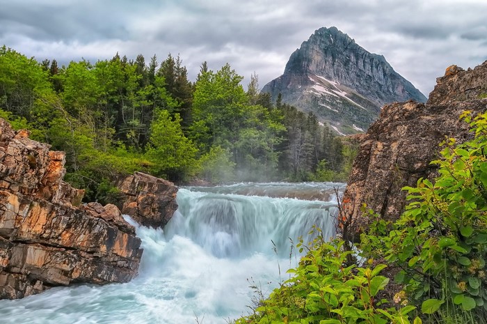 Waterfall cascading over rocks with a mountain in the background