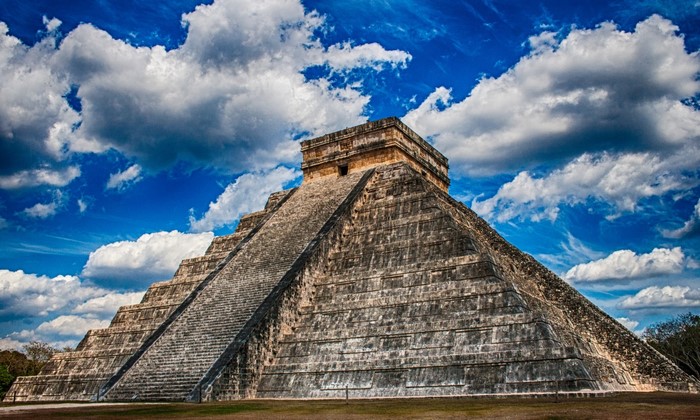 Chichen Itza pyramid under a cloudy blue sky