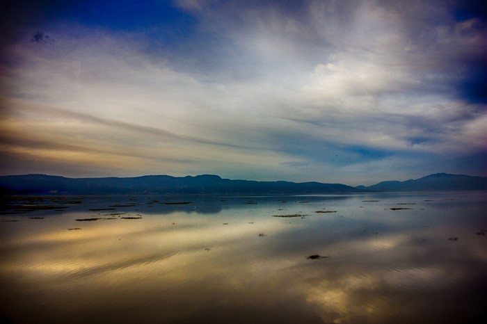 Lake reflection at sunset with mountains and clouds