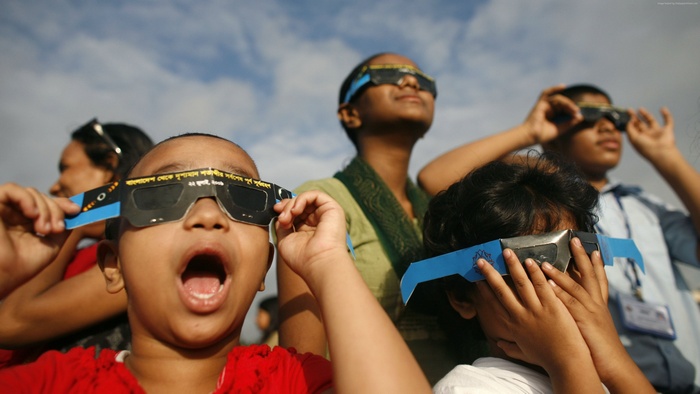 Children watching a solar eclipse with special glasses