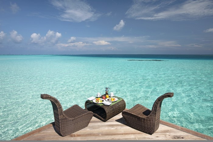 Breakfast table set on a wooden deck overlooking the ocean