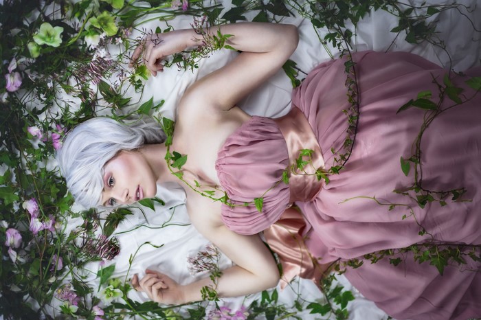 Woman in pink dress surrounded by flowers and vines
