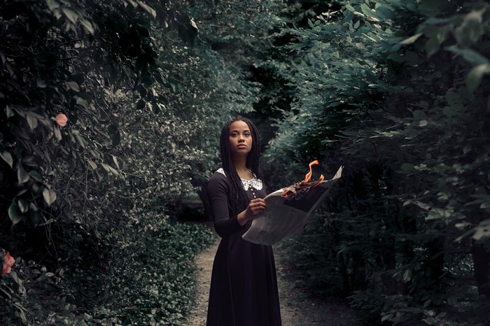 Woman holding burning newspaper in forest