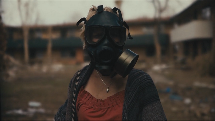 Woman wearing a gas mask in an abandoned setting