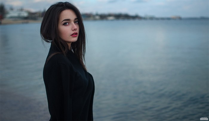 Woman with dark hair and red lipstick by the water