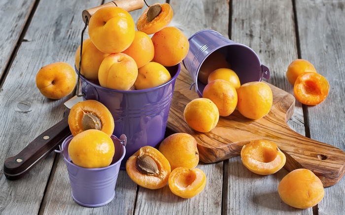 Apricots in purple buckets on wooden table