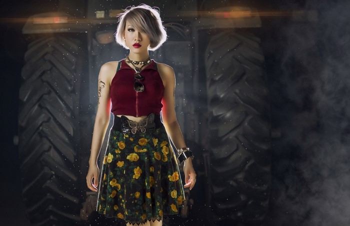 Woman in floral skirt and red top in front of tractor