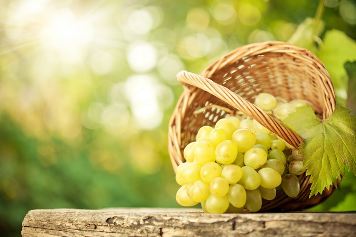 Basket of green grapes on a wooden table