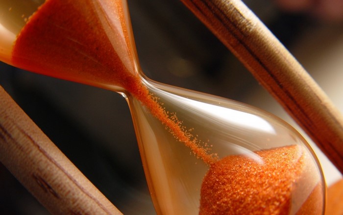 Close-up of an hourglass with orange sand falling