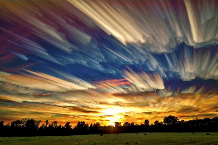 Streaky clouds at sunset over a field