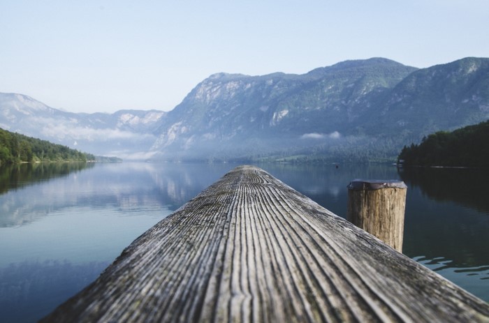 Wooden dock on a calm lake with mountains in the background