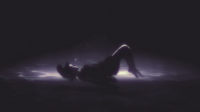 Woman floating underwater in darkness