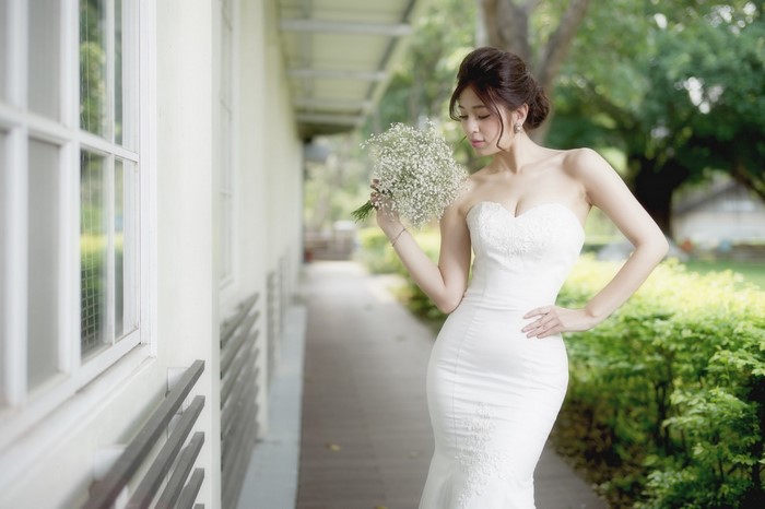 Elegant Bride in White Wedding Gown Holding Flowers