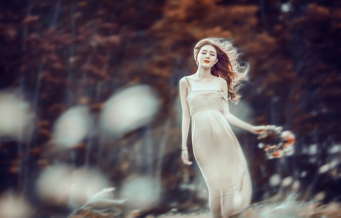 Woman in a light dress holding flowers in a forest