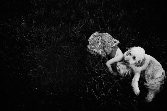 Girl and dog lying in grass