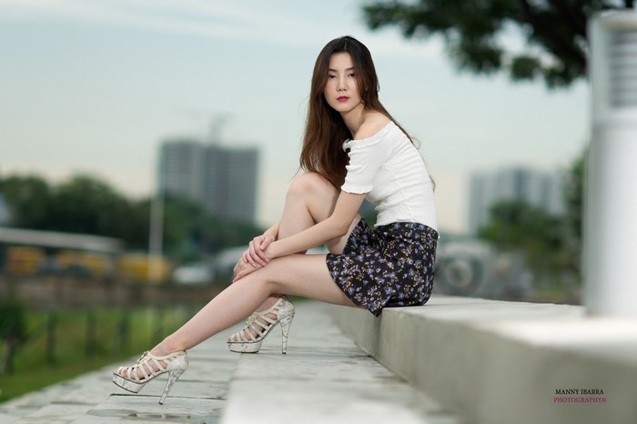Elegant Woman in White Top and Floral Skirt Sitting Outdoors