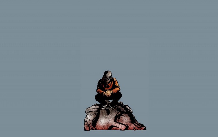 Person in gas mask sitting on rock