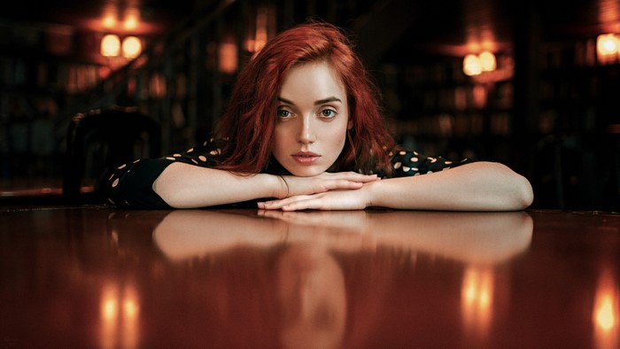 Woman with red hair resting her arms on a table