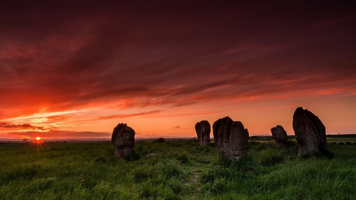 Standing stones at sunset in a grassy field