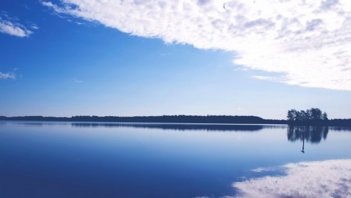 Calm lake with reflection of trees and clouds
