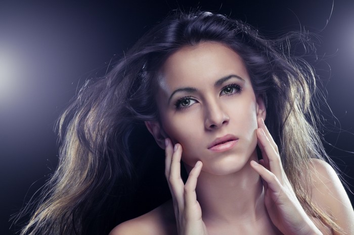 Woman with long flowing hair and hands on face