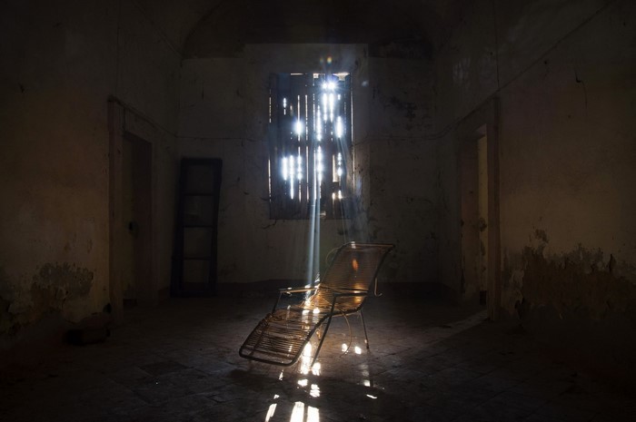 Sunlight streaming into an abandoned room with a chair