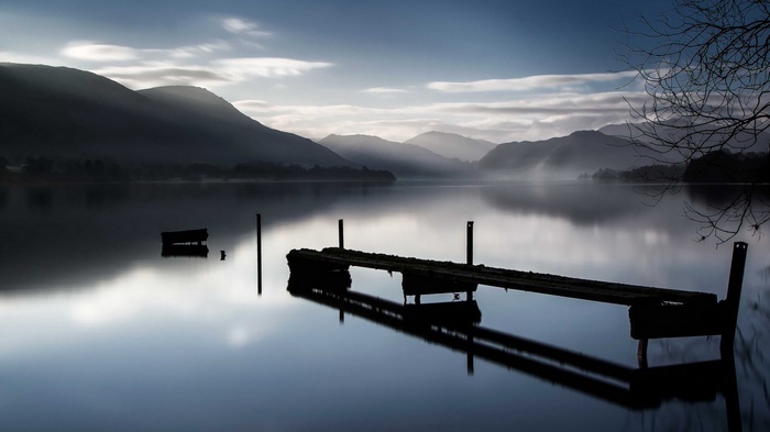Misty lake with a wooden pier and mountains
